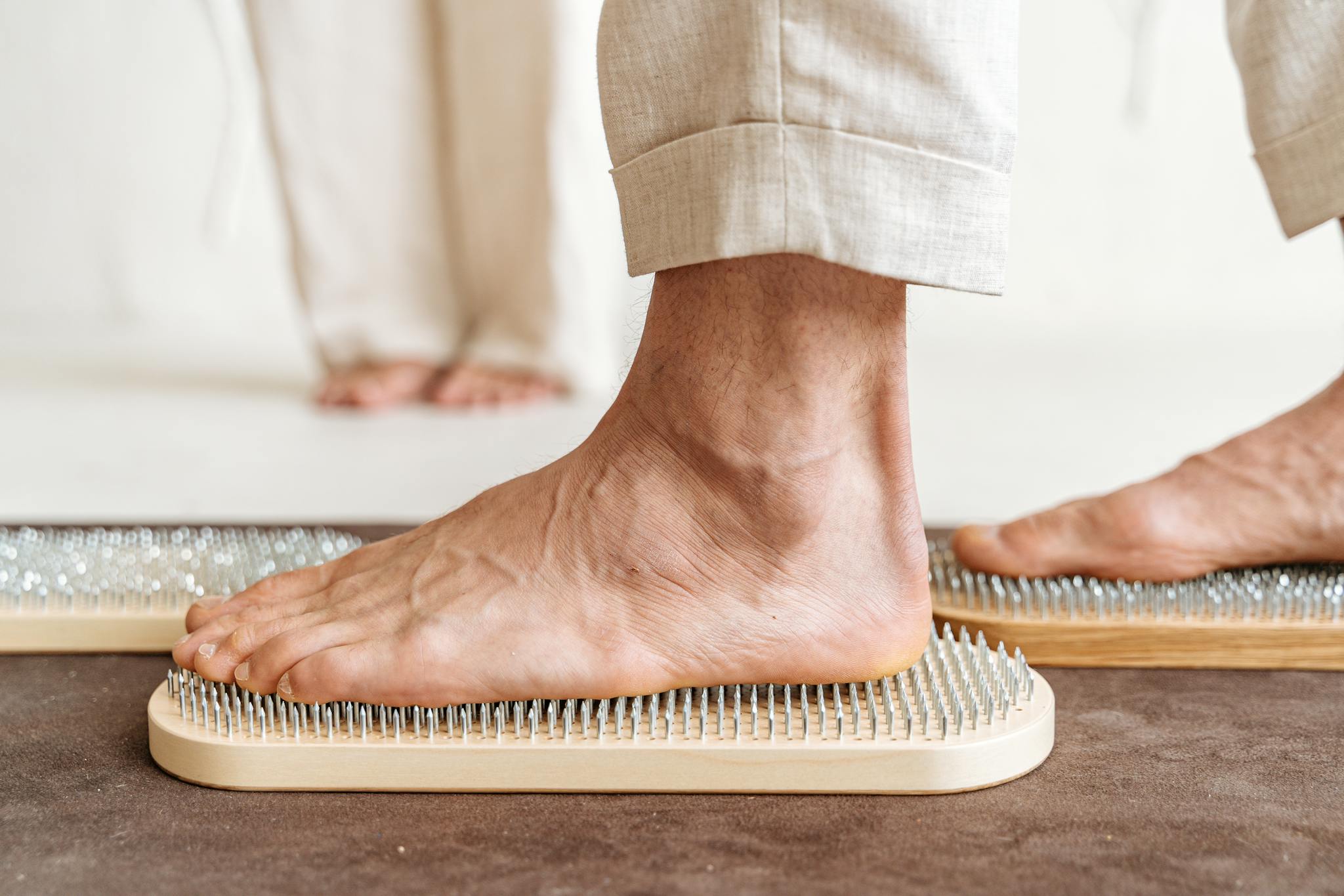 A detailed close-up of a foot stepping on a Sadhu board for acupressure therapy.